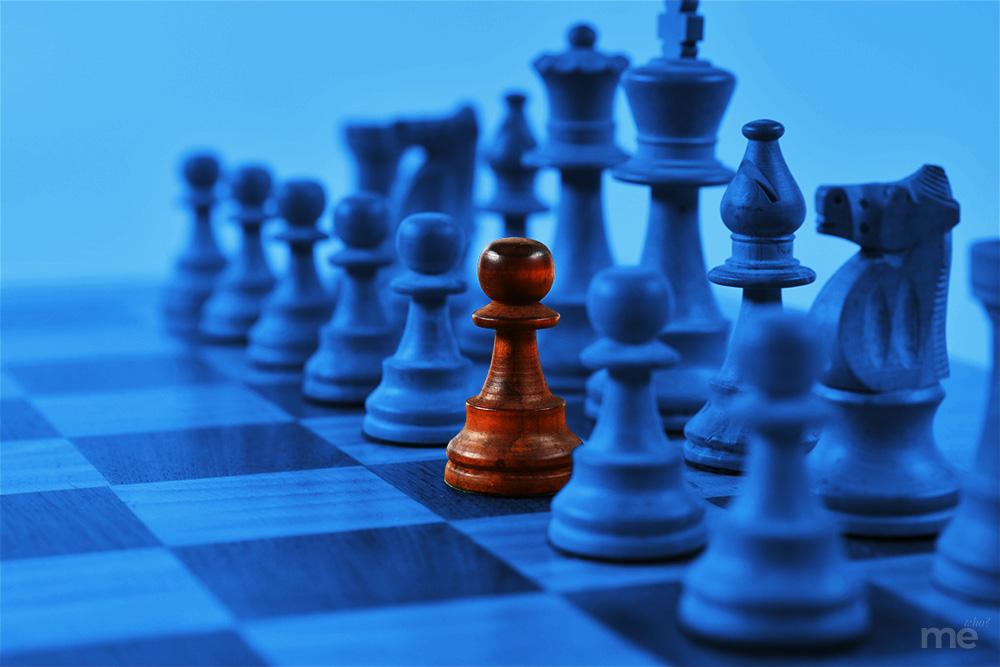 A close-up of a wooden chessboard with a shallow depth of field. All the chess pieces are tinted in a cool, deep blue, except for a single pawn in the center that retains its natural, warm orange-wood color, creating a stark visual contrast.